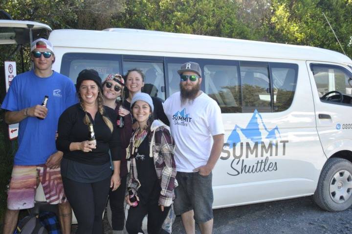 a group of people standing in front of a car posing for the camera