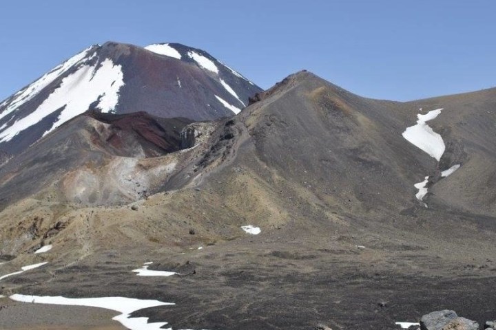 Snow-capped mountain peaks under a clear blue sky, with barren rocky terrain.